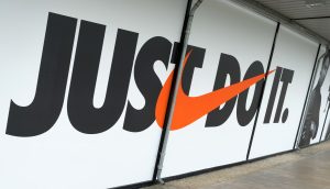 Großes Wanddisplay mit dem Nike-Slogan „JUST DO IT“ mit dem orangefarbenen Nike-Swoosh anstelle des Buchstabens „O“.