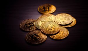 Ein Stapel goldfarbener physischer Münzen mit dem Bitcoin-Symbol wird auf einer dunklen Holzoberfläche präsentiert und hebt die greifbare Seite von Bitcoin hervor.