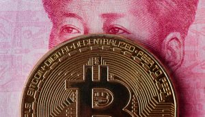 Eine Bitcoin-Münze, die vor einem Teil einer chinesischen Yuan-Banknote platziert ist und das Porträt teilweise verdeckt.