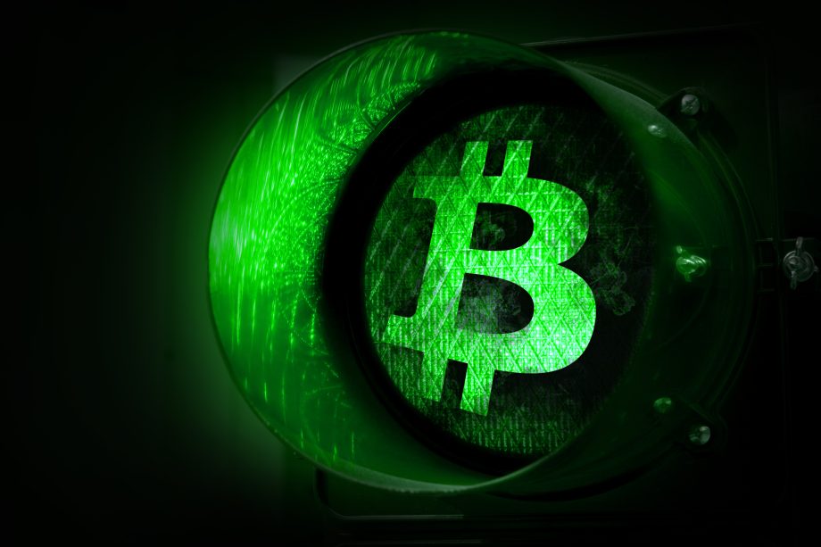 Eine grüne Ampel mit dem leuchtenden Bitcoin-Symbol in der Mitte steht für die Zulassung einer Kryptowährung bzw. Blockchain, da Bitcoin die 100.000-US-Dollar-Marke anstrebt.