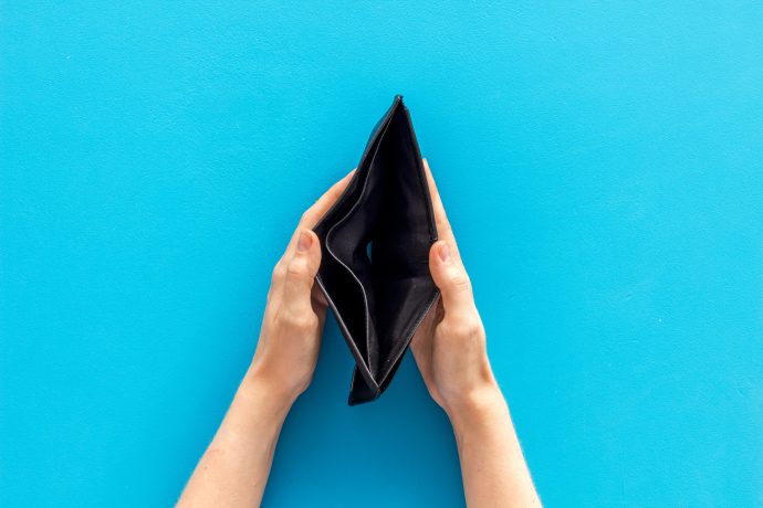 Zwei Hände halten vor einem leuchtend blauen Hintergrund eine leere schwarze Brieftasche offen und deuten damit die Suche nach Bitcoin an.