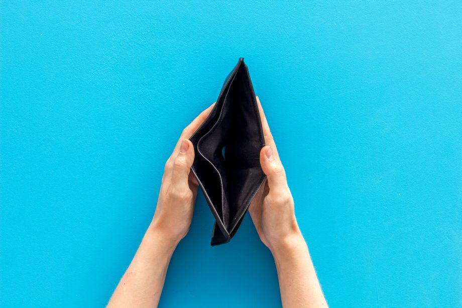 Zwei Hände halten vor einem leuchtend blauen Hintergrund eine leere schwarze Brieftasche offen und deuten damit die Suche nach Bitcoin an.