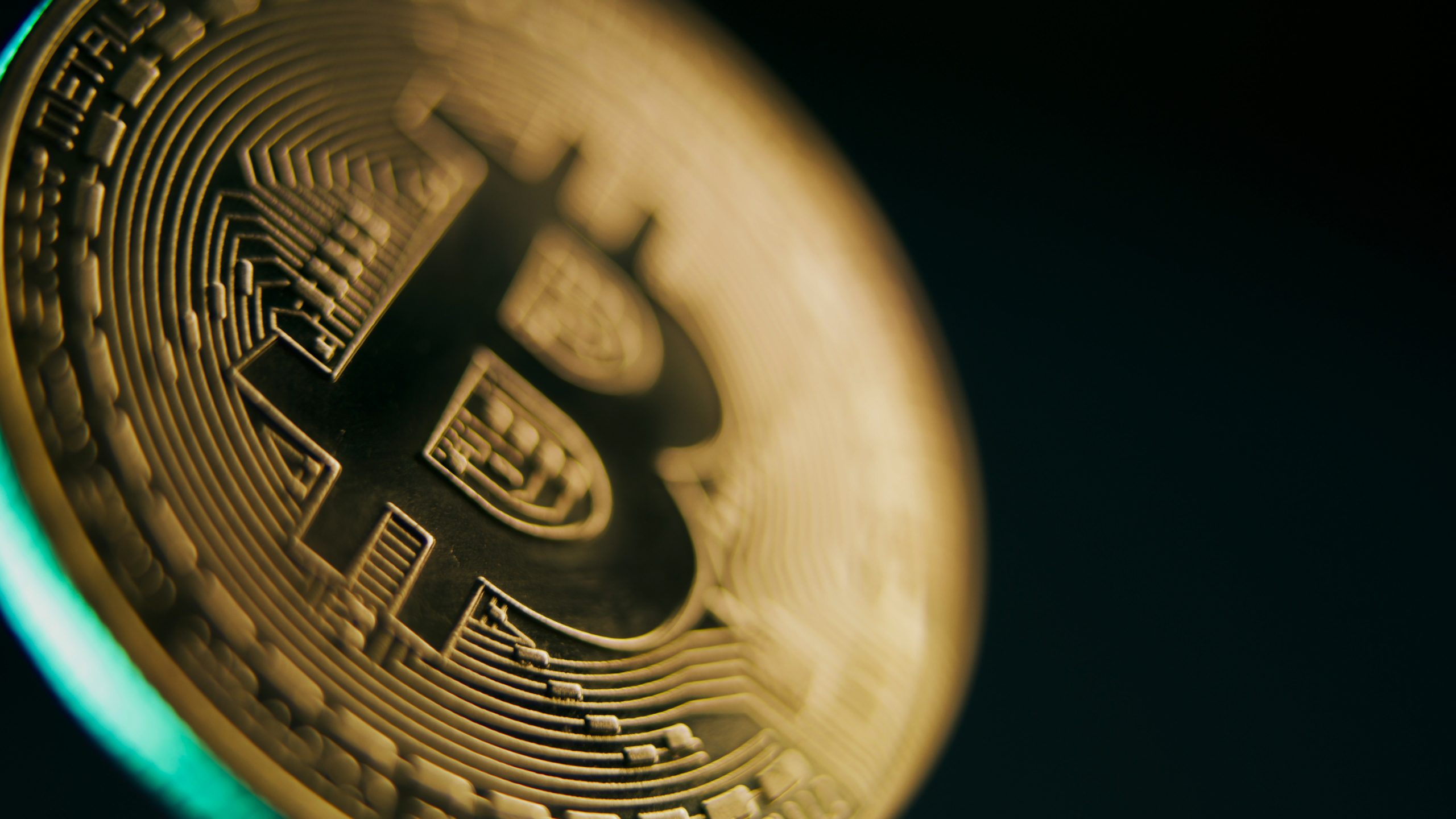 Nahaufnahme einer goldfarbenen physischen Bitcoin-Münze, die den Angebotsschock auf dem Markt symbolisiert, mit komplizierten Schaltkreisen und dem Bitcoin-Logo auf dunklem Hintergrund.