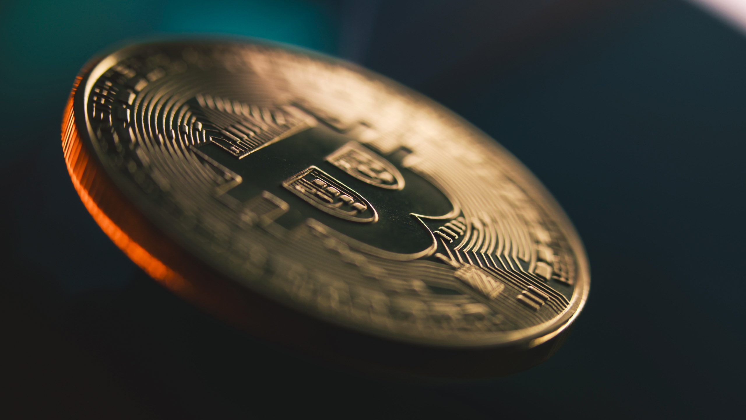 Nahaufnahme einer physischen Bitcoin-Münze mit komplizierten Schaltkreismustern und dem Bitcoin-Symbol, die vor einem unscharfen, dunklen Hintergrund Neulinge dazu einlädt, in die Welt der Kryptowährung einzusteigen.