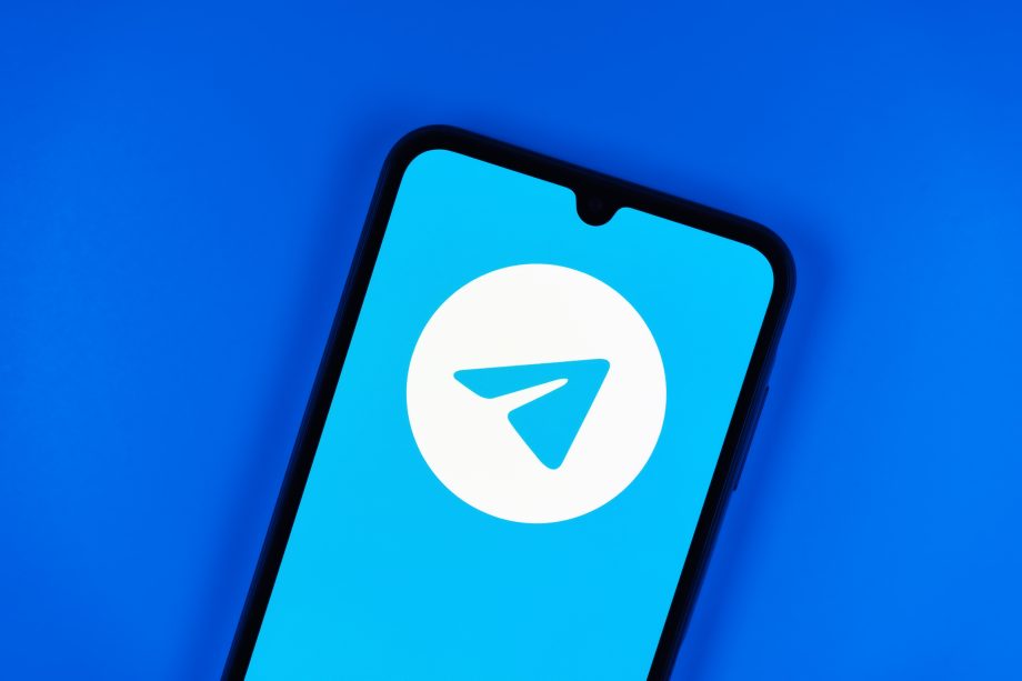 Auf einem Smartphone-Bildschirm wird das Logo der Telegram-App angezeigt, ein weißes Papierflugzeug auf blauem Grund vor einem einfarbig blauen Hintergrund.