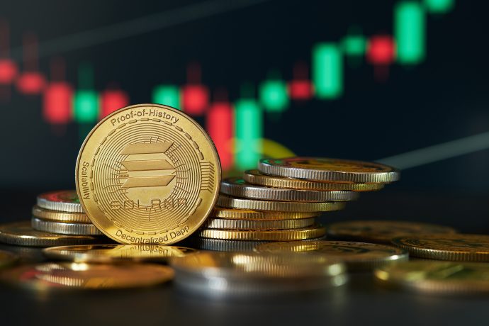 Ein Stapel Solana-Münzen liegt prominent vor einem digitalen Aktienchart mit leuchtend grünen und roten Kerzen und deutet auf die dynamische Einführung des Solana Spot-ETF in Kanada hin.