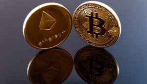 Zwei physische Münzen, die die Kryptowährungen Ethereum und Bitcoin repräsentieren, stehen aufrecht auf einer reflektierenden schwarzen Oberfläche und symbolisieren, wie die Bitcoin-Dominanz schnell steigt, während die Ethereum-Dominanz in der Kryptolandschaft weiterhin von Bedeutung bleibt.