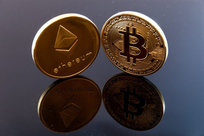 Zwei physische Münzen, die die Kryptowährungen Ethereum und Bitcoin repräsentieren, stehen aufrecht auf einer reflektierenden schwarzen Oberfläche und symbolisieren, wie die Bitcoin-Dominanz schnell steigt, während die Ethereum-Dominanz in der Kryptolandschaft weiterhin von Bedeutung bleibt.