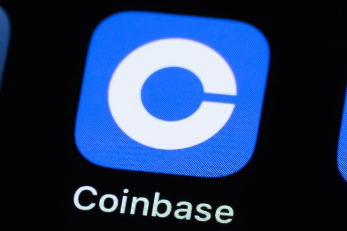 Nahaufnahme des Coinbase-App-Logos, ein weißes C auf blauem quadratischem Hintergrund, angezeigt auf einem Bildschirm mit dem App-Namen Coinbase darunter.