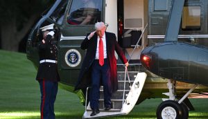 Donald Trump in Anzug und roter Krawatte salutiert beim Verlassen eines Hubschraubers mit dem Präsidentensiegel, während draußen ein uniformierter Marine salutiert – und fängt damit die Formalität ein, bevor Diskussionen über Krypto bei einem Krypto-Dinner von Trump Empörung auslösen.
