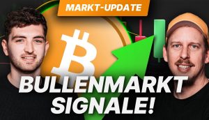 Auf beiden Seiten eines großen Bitcoin-Symbols erscheinen zwei Männer mit einem grünen Aufwärtspfeil und Kerzendiagrammen im Hintergrund. Der Text lautet: Bullenmarkt Signale! Markt-Update. Jetzt im Livestream über Kryptowährungen und Bitcoin informieren!.