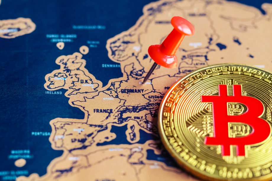Eine goldene Bitcoin-Münze und eine rote Stecknadel, die Deutschland auf einer Europakarte markiert, verdeutlichen das wachsende Interesse an Bitcoin, insbesondere angesichts seines jüngsten Allzeithochs.