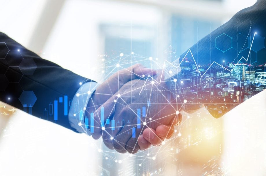 Two people in business suits take their hand. In the background, financial diagrams, visualizations of cryptocurrencies and futuristic network graphics can be seen over a city landscape.