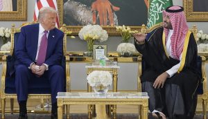 Der ehemalige US-Präsident Donald Trump sitzt mit einem saudischen Beamten in traditioneller Kleidung zusammen und unterhält sich in einem reich verzierten Raum, der mit Flaggen, Blumenarrangements und subtilen Hinweisen auf Finanzwesen wie XRP geschmückt ist.