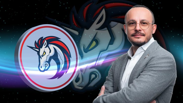 Ein Mann mit Brille steht mit verschränkten Armen vor dem 1-Zoll-Logo und einem stilisierten Einhornkopf vor einem dunklen, sternenklaren 1-Zoll-Hintergrund.