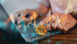 Eine Person tippt auf einem Laptop, im Vordergrund ist eine physische Bitcoin-Münze zu sehen, und aufwärts zeigende Finanzdiagramme symbolisieren den Handel mit Kryptowährungen oder Investitionen mit Revolut für europäische Kunden.