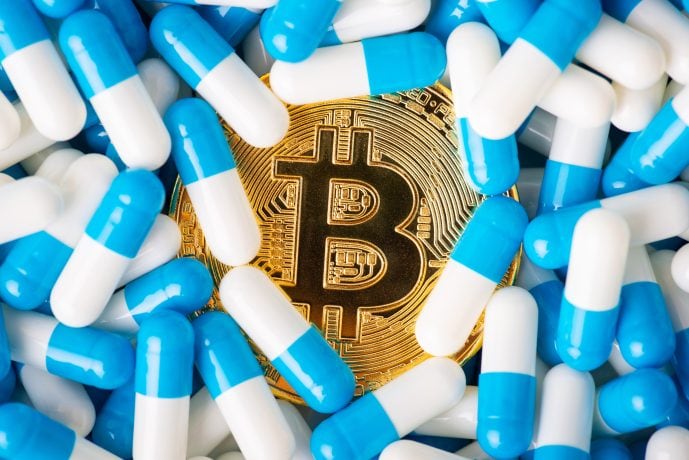 Eine goldene Bitcoin-Münze, umgeben von verstreuten blauen und weißen Kapseln, symbolisiert die innovative Strategie von Semler Scientific bei der Navigation durch die sich entwickelnde Bitcoin-Kurslandschaft.