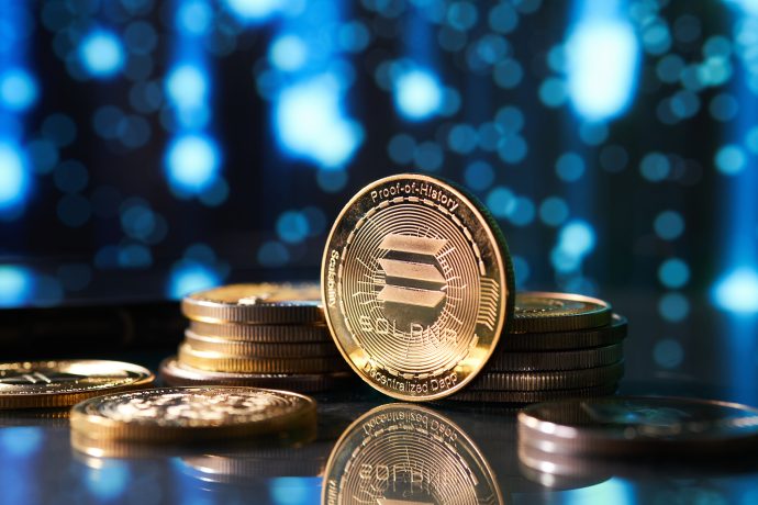 Eine Nahaufnahme gestapelter Solana-Münzen auf einer reflektierenden Oberfläche mit unscharfem blauen Hintergrund, die auf das wachsende Interesse an einem potenziellen Solana-ETF hindeutet.