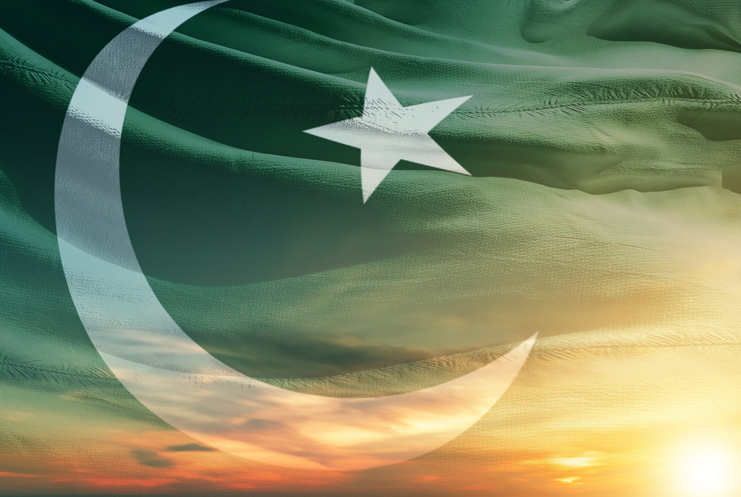 Die pakistanische Flagge mit einem weißen Stern und einer Mondsichel auf grünem Grund ist über einen Sonnenuntergangshimmel mit strukturierten Wolken gelegt und spiegelt auf subtile Weise den Aufstieg des Bitcoin-Minings in Pakistan in der digitalen Landschaft des Landes wider.