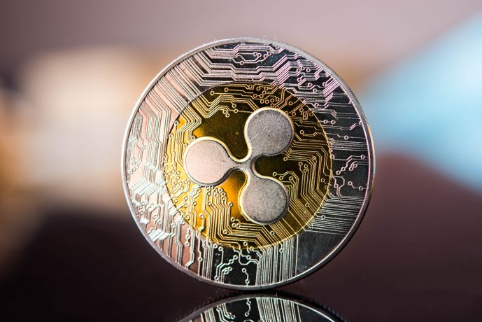 Eine Nahaufnahme einer physischen Münze mit dem Kryptowährungslogo Ripple (XRP) und schaltungsähnlichen Mustern auf ihrer Oberfläche.