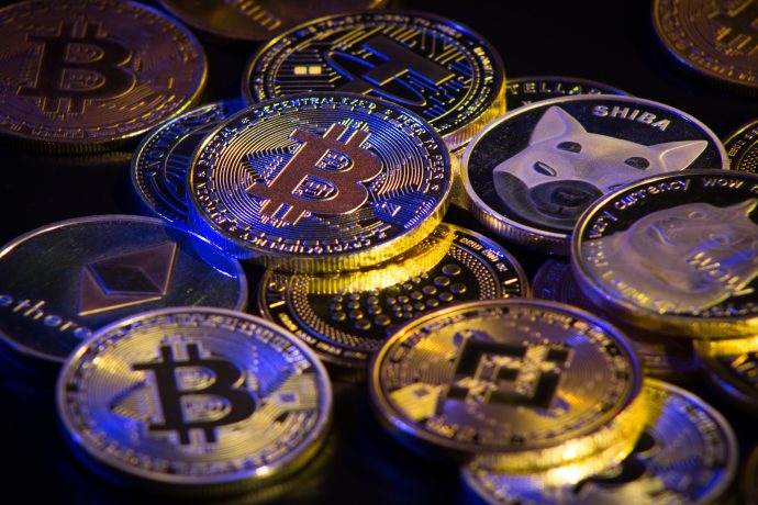 Eine Sammlung physischer Münzen, die verschiedene Kryptowährungen repräsentieren – darunter Bitcoin, Ethereum, Shiba Inu und Dogecoin –, werden dicht beieinander ausgestellt als Anspielung auf den lebhaften Krypto-Markt.