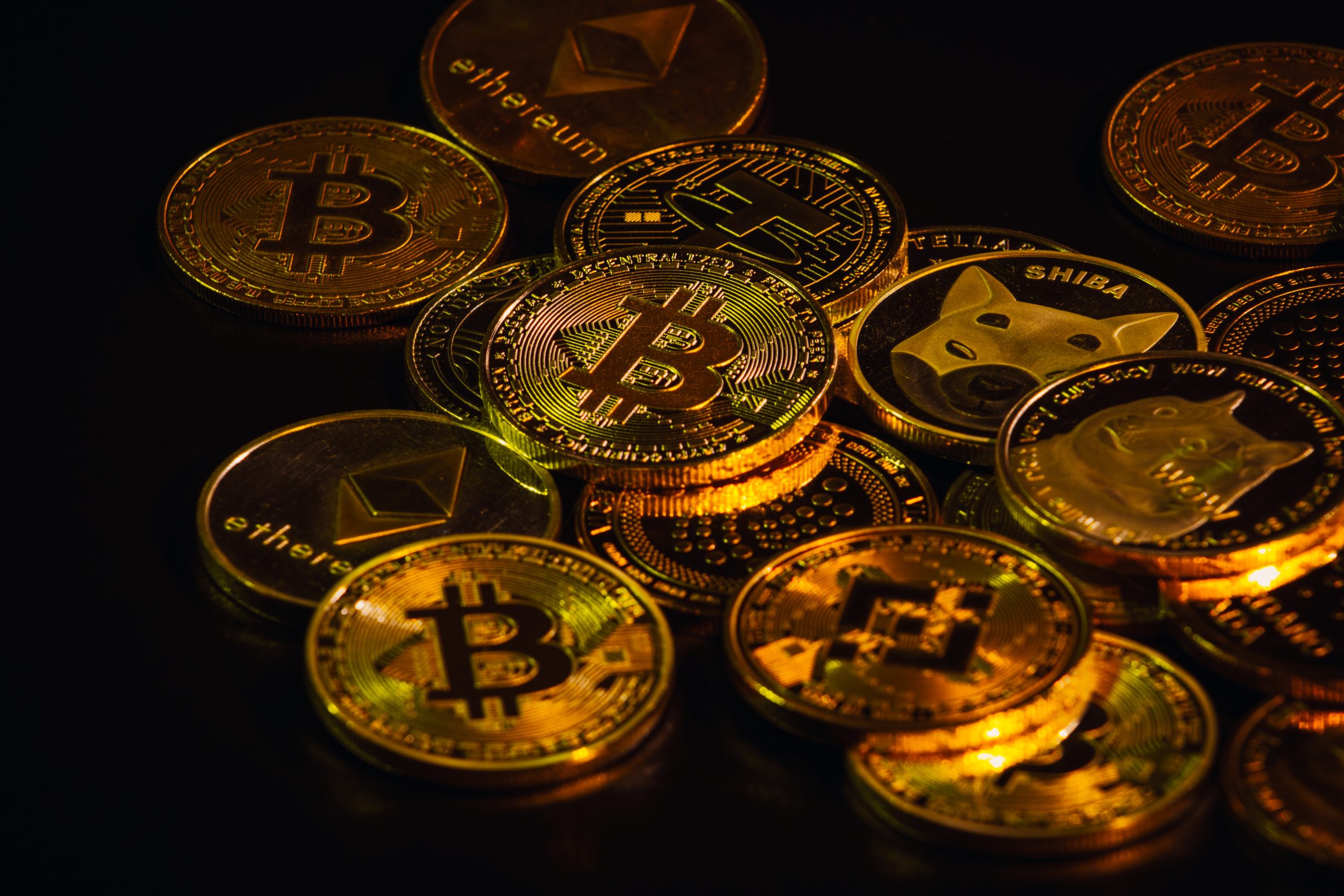 Auf einer dunklen Oberfläche wird ein Stapel verschiedener physischer Kryptowährungsmünzen angezeigt, darunter Bitcoin, Ethereum, Binance Coin und Dogecoin – was das wachsende Interesse an digitalen Vermögenswerten in Thailand widerspiegelt.