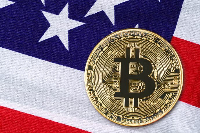 Eine Bitcoin-Münze vor einer US-Flagge