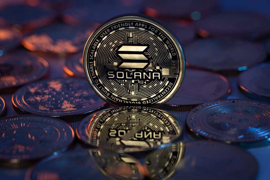 Eine Solana-Kryptowährungsmünze steht aufrecht zwischen anderen Münzen und zeigt deutlich das Solana-Logo und das komplizierte Schaltkreisdesign.