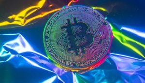 Ein physischer Bitcoin-Token liegt auf einem zerknitterten, schillernden Hintergrund, dessen Oberfläche Regenbogenfarben reflektiert – eine inspirierende Szene für Profis, die neue Handelsindikatoren erkunden.