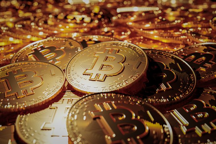 Ein Stapel glänzender goldfarbener Münzen mit dem Bitcoin-Logo, das die Welt von Bitcoin und Kryptowährungen symbolisiert.