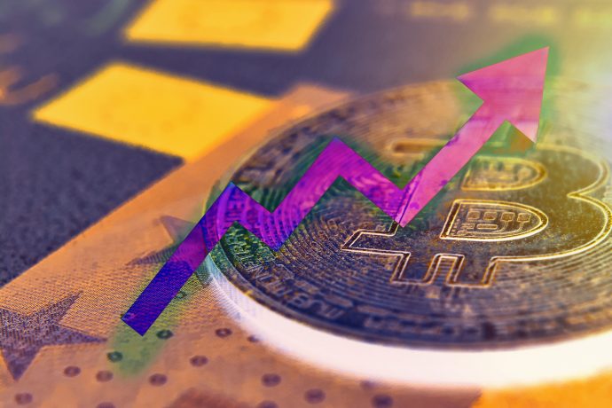 Eine Nahaufnahme einer Bitcoin-Münze zeigt einen auffälligen violetten, nach oben zeigenden Pfeil, der den steigenden Wert von Bitcoin auf dem Kryptowährungsmarkt symbolisiert.