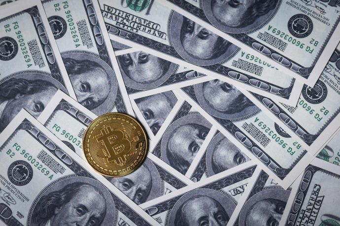 Eine goldene Bitcoin-Münze auf überlappenden 100-Dollar-Scheinen der USA verdeutlicht den wachsenden Einfluss von Bitcoin und Metaplanet in der Finanzlandschaft.