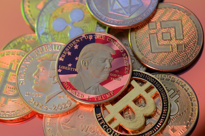 TRUMP Memecoin Crash: Trump-Coin liegt zwischen Krypto-Münzen und Bitcoin-Symbol als Hinweis auf starke Kursverluste
