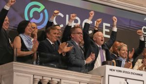 Eine Gruppe von Menschen feiert auf einem Balkon der New Yorker Börse, lächelt und reckt ihre Fäuste in der Nähe eines Podiums und einer großen Glocke während des Börsengangs der Circle-Aktie.