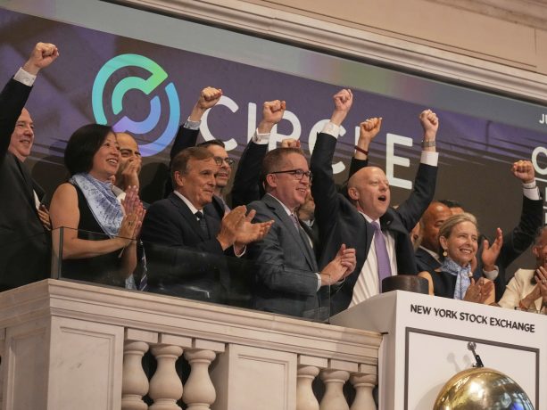 Eine Gruppe von Menschen feiert auf einem Balkon der New Yorker Börse, lächelt und reckt ihre Fäuste in der Nähe eines Podiums und einer großen Glocke während des Börsengangs der Circle-Aktie.