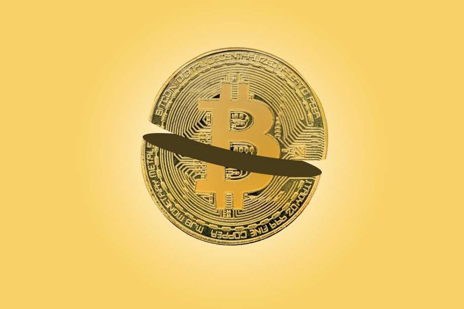 Eine goldene Bitcoin-Münze mit einem schwarzen horizontalen Schrägstrich in der Mitte auf gelbem Hintergrund, der die Auswirkungen der Bitcoin-Halbierung auf den Bitcoin-Kurs symbolisiert.