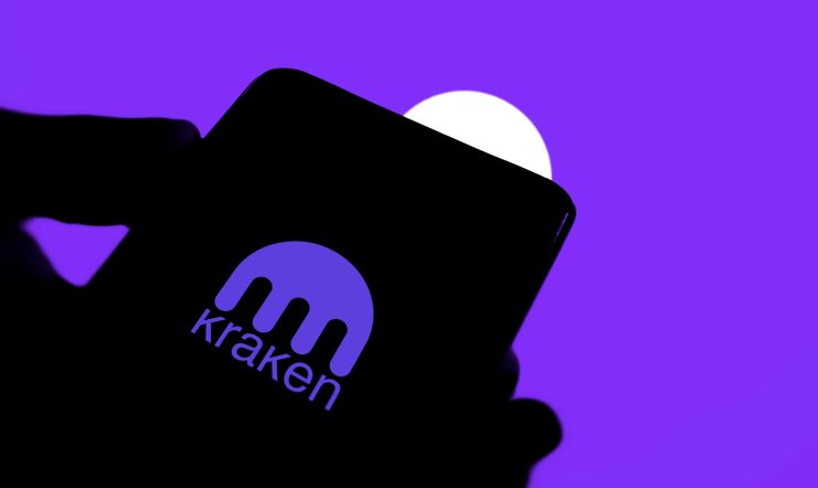 Ein Smartphone zeigt das Logo der Kraken-App vor einem lila Hintergrund mit einem weißen Kreis.
