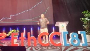 Aave-Gründer Stani Kulechov präsentiert eine Finanzdatengrafik mit dem Titel The Financial System is Getting Onchain auf der EthCC[8] und hebt dabei Aave hervor, mit roten Stühlen und Bühnenbeleuchtung im Hintergrund.
