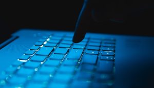 Eine Nahaufnahme des Fingers einer Person, die gerade eine Taste auf einer beleuchteten Laptop-Tastatur in einer dunklen Umgebung drückt, was darauf hindeutet, dass eine Ethereum-Transaktion durchgeführt werden soll.