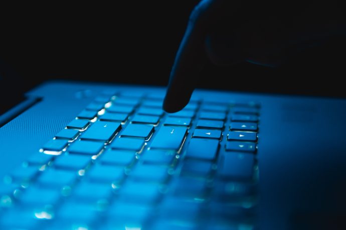 Eine Nahaufnahme des Fingers einer Person, die gerade eine Taste auf einer beleuchteten Laptop-Tastatur in einer dunklen Umgebung drückt, was darauf hindeutet, dass eine Ethereum-Transaktion durchgeführt werden soll.