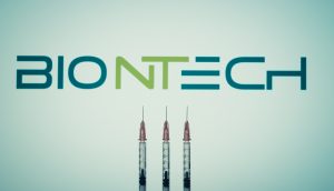 Drei Spritzen sind vor einem unscharfen BioNTech-Logo aufgereiht und heben die medizinischen Innovationen von BioNTech auf einem hellen Hintergrund hervor.