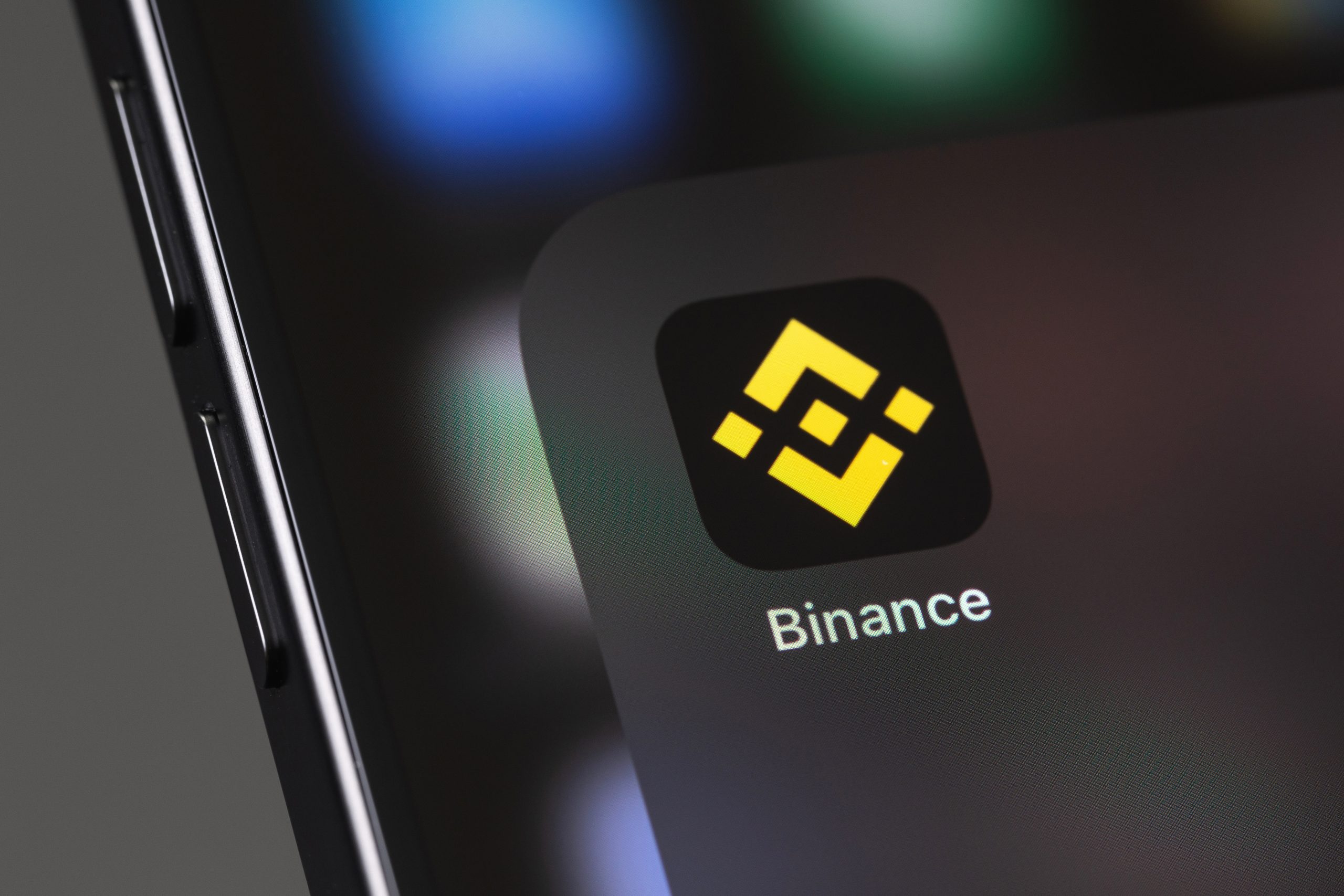 Nahaufnahme eines Smartphone-Bildschirms mit dem Binance-App-Symbol und dem charakteristischen gelben geometrischen Binance-Logo auf schwarzem Hintergrund.