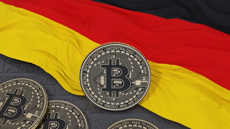 Ein Stapel Bitcoin-Token liegt vor einer deutschen Flagge und verdeutlicht den wachsenden Einfluss von Bitcoin in Deutschland.