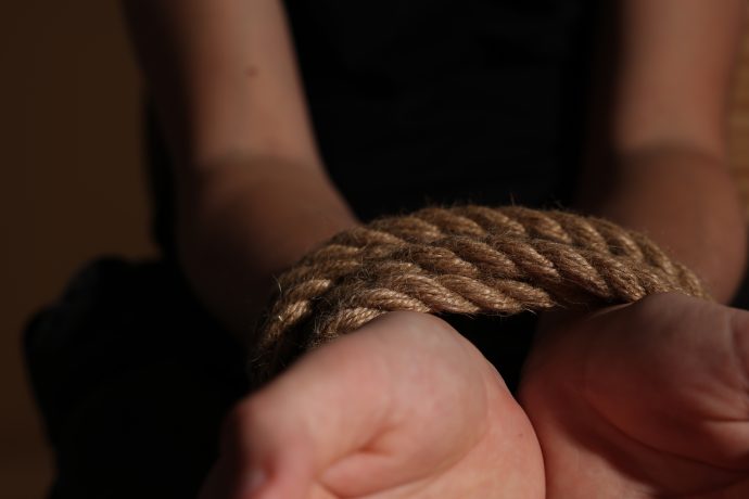 Die Handgelenke einer Person sind mit einem dicken Seil fest zusammengebunden - nach Krypto-Art -, wobei die Hände nach oben zeigen und im Vordergrund zu sehen sind.