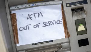 Ein handgeschriebenes Schild mit der Aufschrift "ATM OUT OF SERVICE" (Geldautomat außer Betrieb) ist über den Geldschlitz eines Geldautomaten geklebt