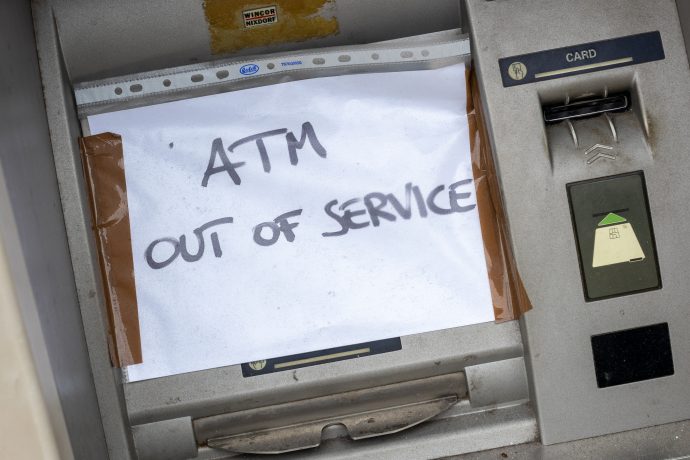 Ein handgeschriebenes Schild mit der Aufschrift "ATM OUT OF SERVICE" (Geldautomat außer Betrieb) ist über den Geldschlitz eines Geldautomaten geklebt