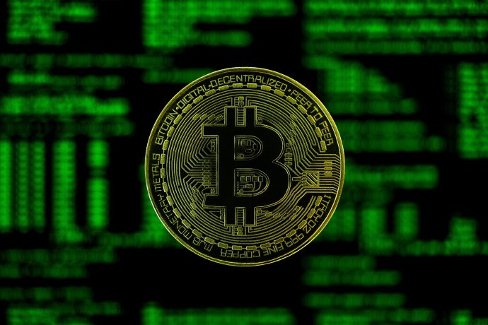 In der Mitte ist ein goldfarbenes Bitcoin-Symbol mit einem grünen digitalen Bitcoin-Code im unscharfen Hintergrund abgebildet.