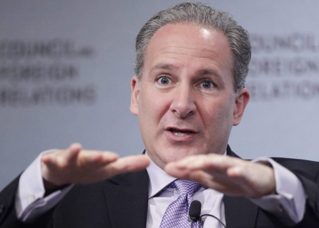 Peter Schiff, im Anzug, gestikuliert mit beiden Händen, während er auf einer öffentlichen Veranstaltung spricht, ein Mikrofon an seiner Krawatte befestigt und ein verschwommener Hintergrund hinter ihm.