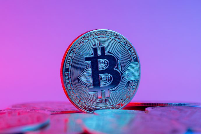 Eine Bitcoin-Münze vor lila Hintergrund