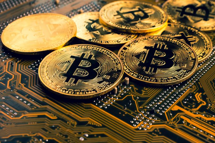 Mehrere goldfarbene Bitcoin-Token liegen auf einer Computerplatine und verdeutlichen die Rolle von Bitcoin bei Kryptowährungen und digitalen Transaktionen.